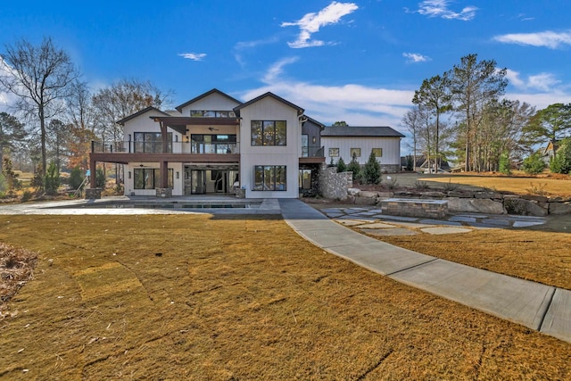 view of front of property featuring a swimming pool, a front lawn, a patio area, and a balcony