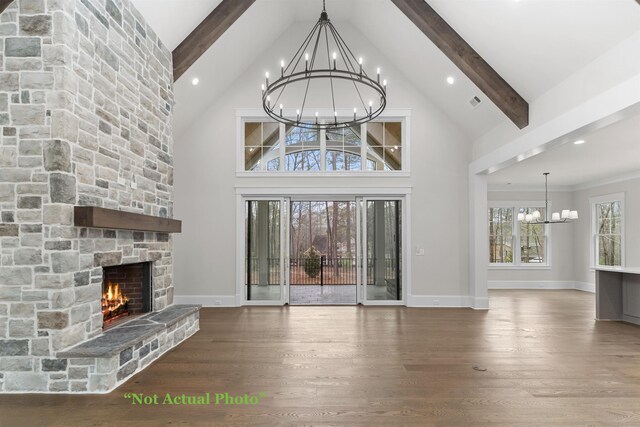 unfurnished living room with beamed ceiling, an inviting chandelier, wood finished floors, and a fireplace