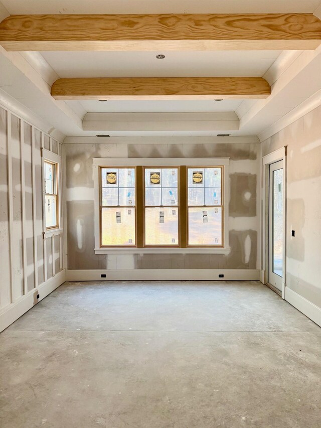 unfurnished room with beam ceiling and concrete floors