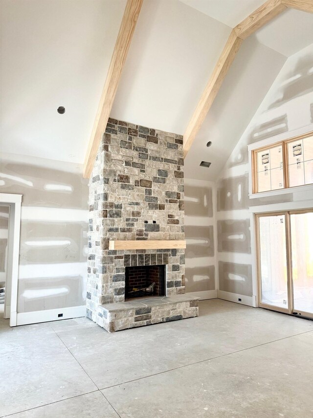 unfurnished living room featuring a stone fireplace, vaulted ceiling with beams, and concrete floors