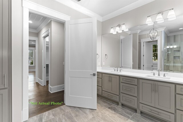 bathroom with a sink, double vanity, crown molding, and an inviting chandelier