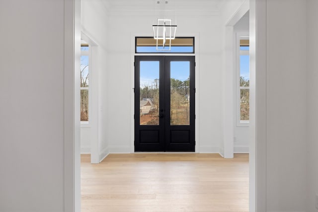 entryway with crown molding, light hardwood / wood-style flooring, and french doors