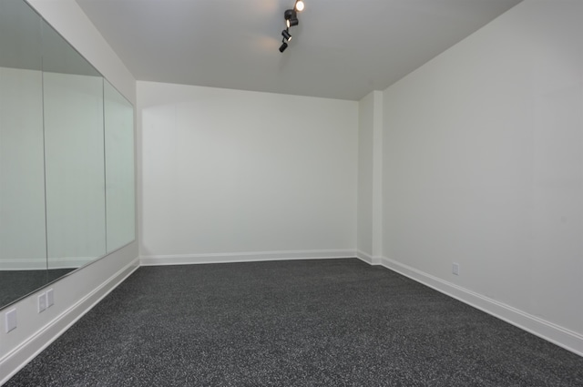 empty room featuring track lighting and baseboards