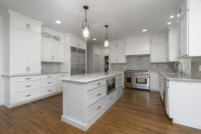 kitchen with custom range hood, high end appliances, white cabinets, and a sink