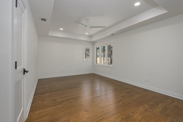 spare room with baseboards, a raised ceiling, a ceiling fan, and dark wood-style flooring