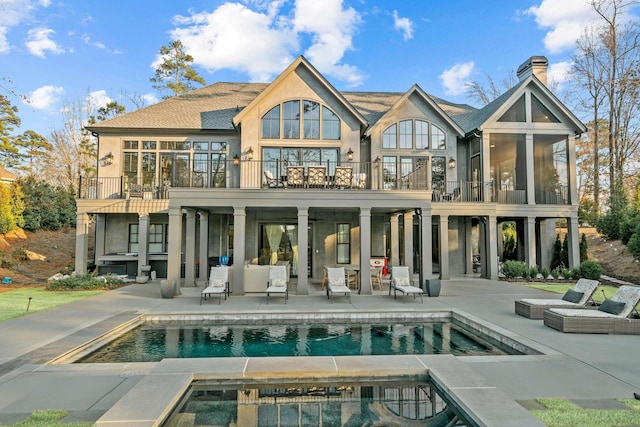 rear view of property featuring stucco siding, an outdoor pool, a patio, and an in ground hot tub