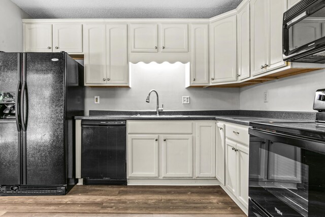 108 Ashwood Pt, Eatonton, GA 31024 - kitchen with black appliances, dark countertops, light wood finished floors, and a sink
