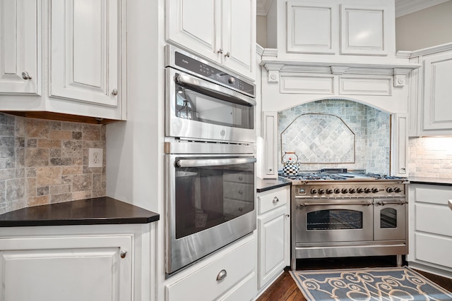 1011 Cartwright Ln, Greensboro, GA 30642 - kitchen featuring appliances with stainless steel finishes, backsplash, white cabinetry, dark countertops, and ornamental molding
