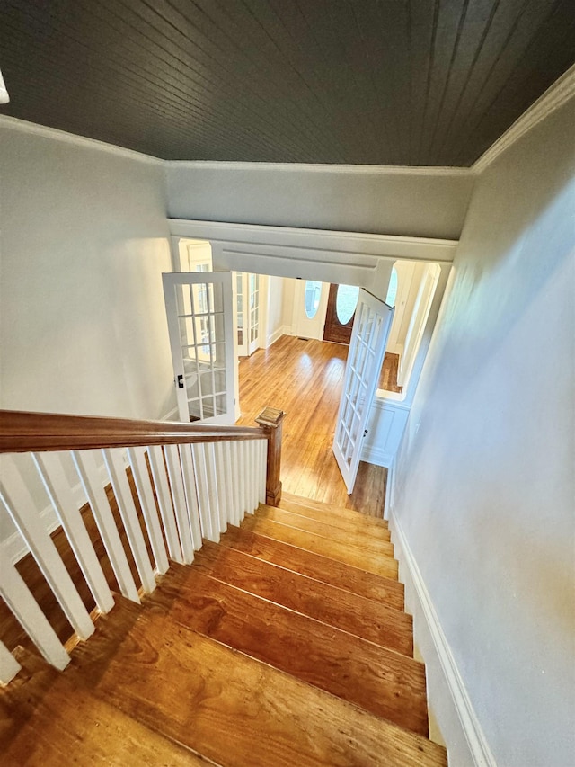 stairway featuring crown molding, hardwood / wood-style flooring, and french doors