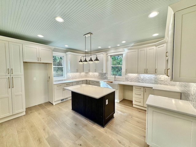 kitchen featuring pendant lighting, white cabinetry, backsplash, light hardwood / wood-style floors, and a kitchen island