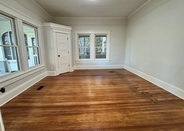 empty room with ornamental molding and dark hardwood / wood-style flooring