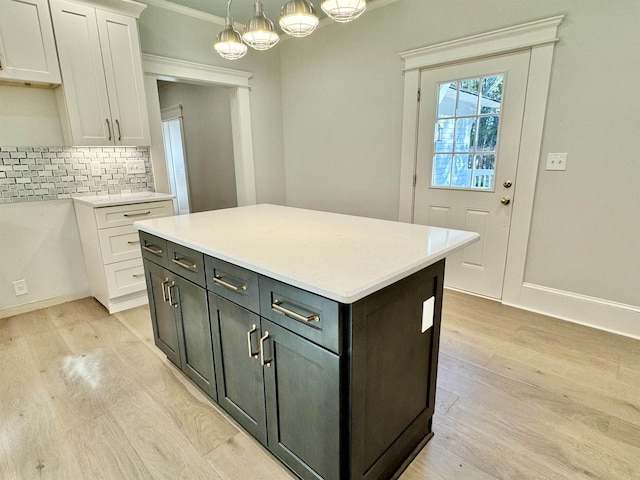 kitchen featuring white cabinetry, a center island, hanging light fixtures, light hardwood / wood-style flooring, and decorative backsplash