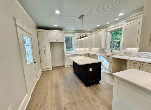 kitchen with sink, light hardwood / wood-style flooring, white cabinetry, hanging light fixtures, and a center island