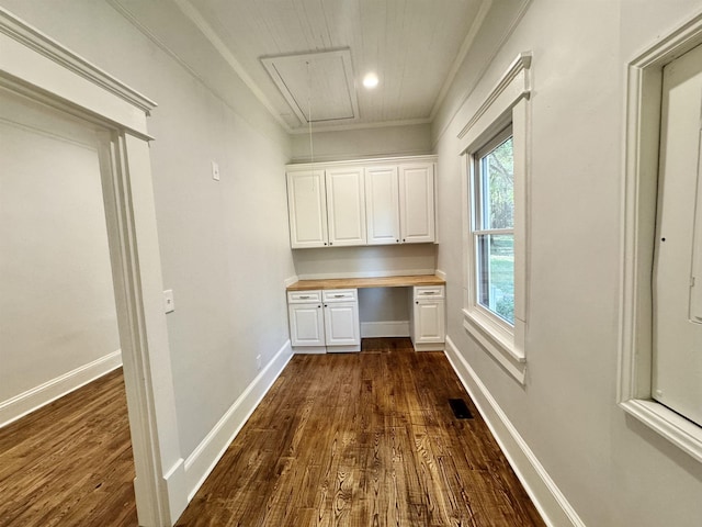 unfurnished office with ornamental molding, dark wood-type flooring, and built in desk