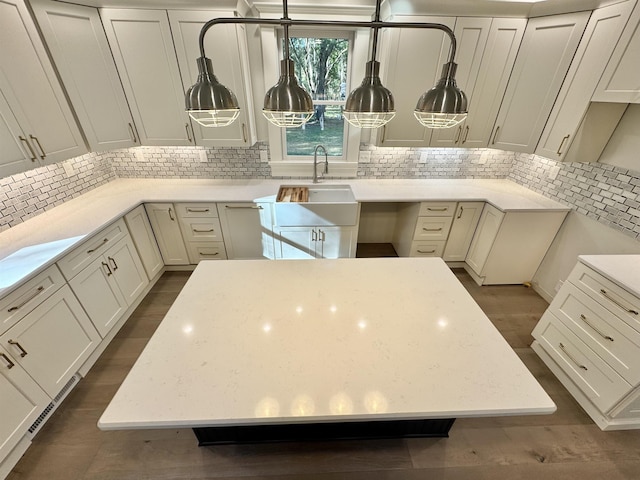 kitchen with sink, light stone counters, a center island, dark hardwood / wood-style flooring, and decorative backsplash