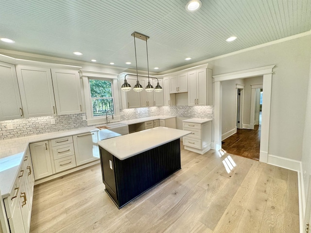 kitchen with hanging light fixtures, light hardwood / wood-style floors, white cabinets, and a kitchen island