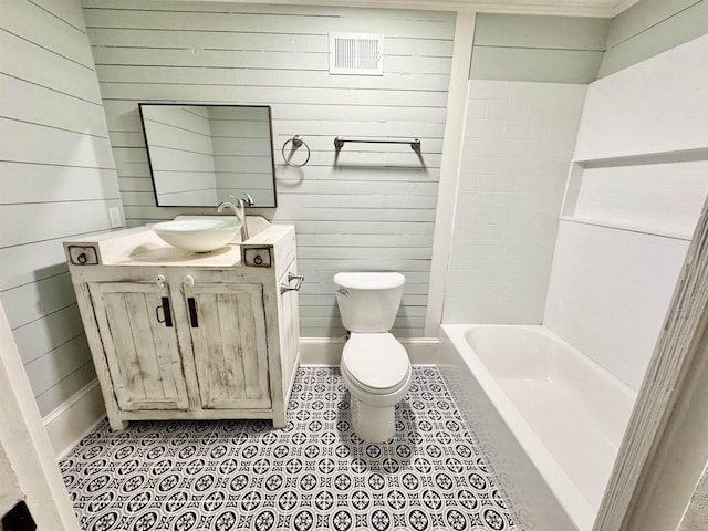 bathroom with tile patterned flooring, vanity, wooden walls, and toilet