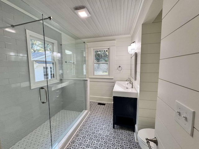 bathroom with tile patterned floors, toilet, ornamental molding, vanity, and a shower with door