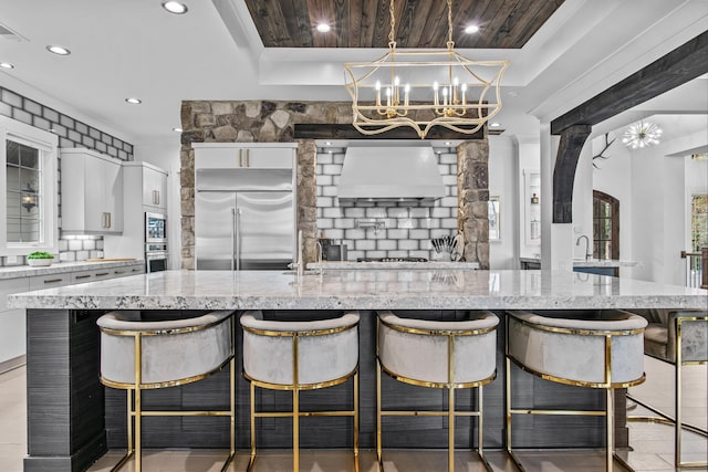 1031 Fish Trap Shls, Greensboro, GA 30642 - kitchen featuring appliances with stainless steel finishes, custom range hood, white cabinets, a breakfast bar, and recessed lighting