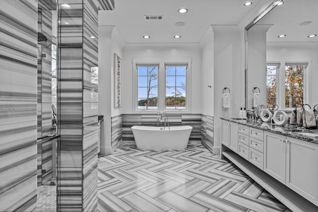 1031 Fish Trap Shls, Greensboro, GA 30642 - full bathroom featuring healthy amount of natural light, double vanity, recessed lighting, a soaking tub, and a wainscoted wall