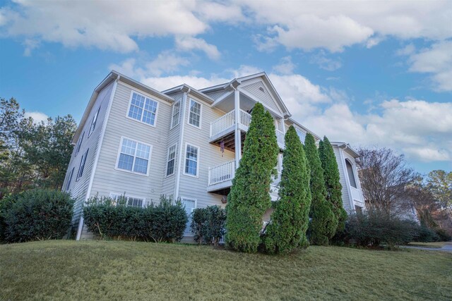 view of home's exterior with a balcony and a lawn