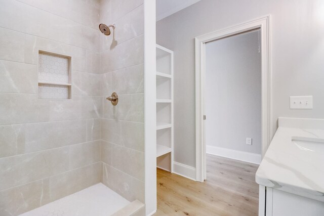 bathroom with vanity, hardwood / wood-style flooring, and tiled shower