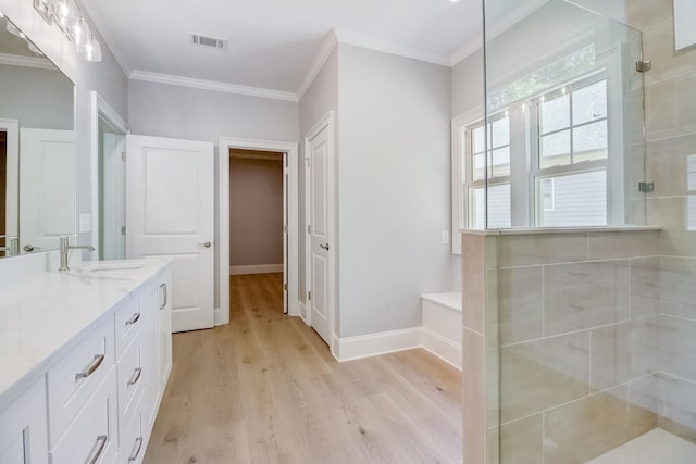 bathroom with hardwood / wood-style floors, crown molding, and a shower with shower door