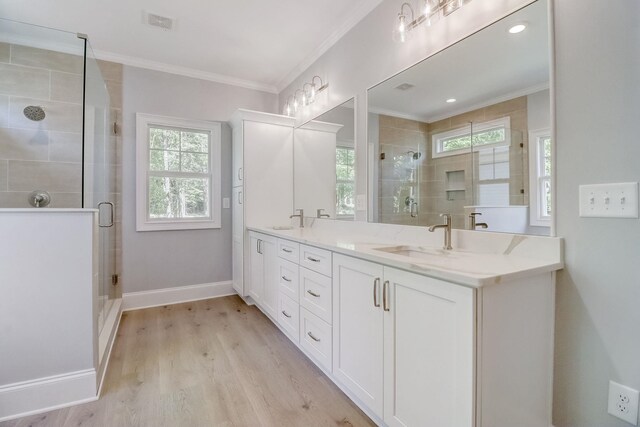 bathroom with ornamental molding, hardwood / wood-style floors, vanity, and a shower with shower door