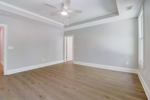 unfurnished room featuring crown molding, ceiling fan, a tray ceiling, and light wood-type flooring