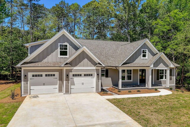 view of front of house with a garage, covered porch, and a front yard