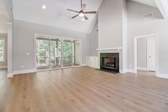 unfurnished living room with ceiling fan, a high end fireplace, high vaulted ceiling, and light wood-type flooring