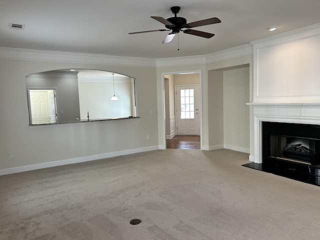 unfurnished living room with carpet floors, ornamental molding, and ceiling fan