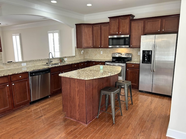 kitchen featuring sink, light hardwood / wood-style floors, kitchen peninsula, stainless steel appliances, and light stone countertops