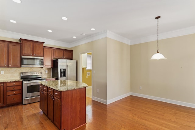 kitchen with pendant lighting, appliances with stainless steel finishes, a center island, and light hardwood / wood-style flooring