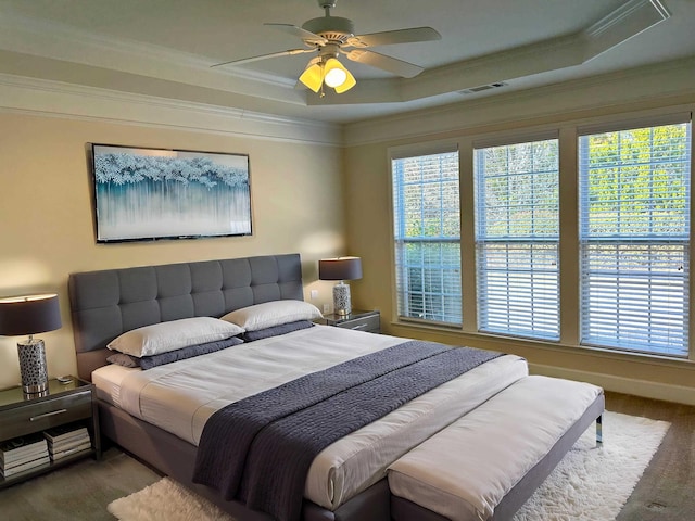 bedroom featuring a raised ceiling, ornamental molding, carpet floors, and ceiling fan