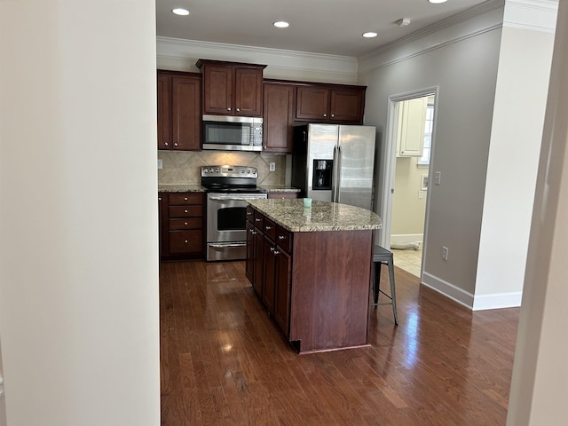 kitchen featuring appliances with stainless steel finishes, backsplash, a kitchen breakfast bar, a center island, and dark brown cabinetry