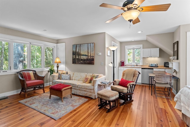 living area with light wood-style flooring, ceiling fan, and baseboards