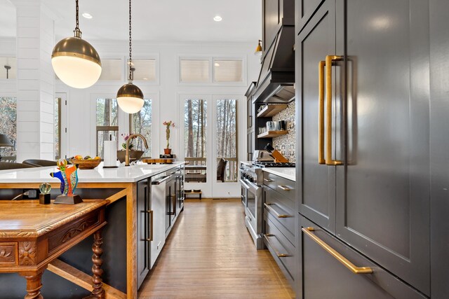 kitchen with pendant lighting, sink, light hardwood / wood-style flooring, high end appliances, and ventilation hood