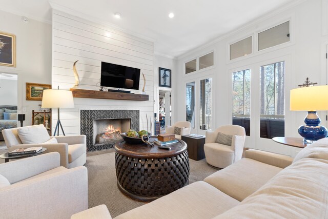 living room with a tiled fireplace, light carpet, and ornamental molding