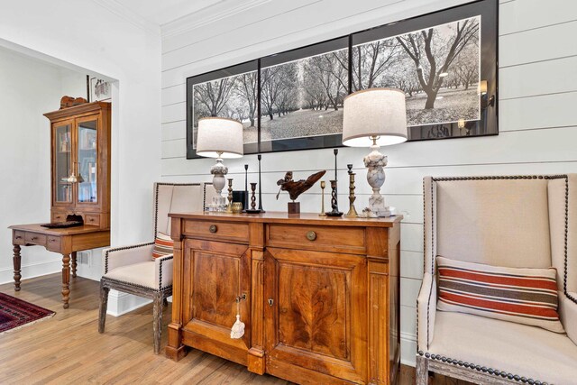 bar featuring crown molding, light hardwood / wood-style floors, and wood walls