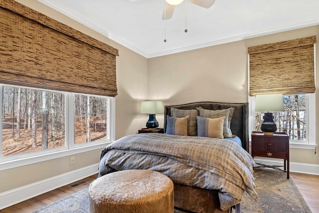 bedroom with hardwood / wood-style floors, ornamental molding, and ceiling fan