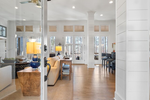 living room with french doors, crown molding, wood-type flooring, ceiling fan, and decorative columns