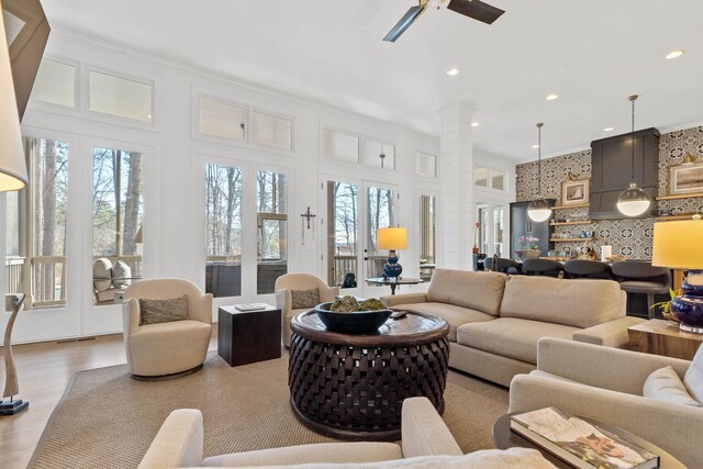 living room featuring a wealth of natural light, french doors, ceiling fan, and ornate columns