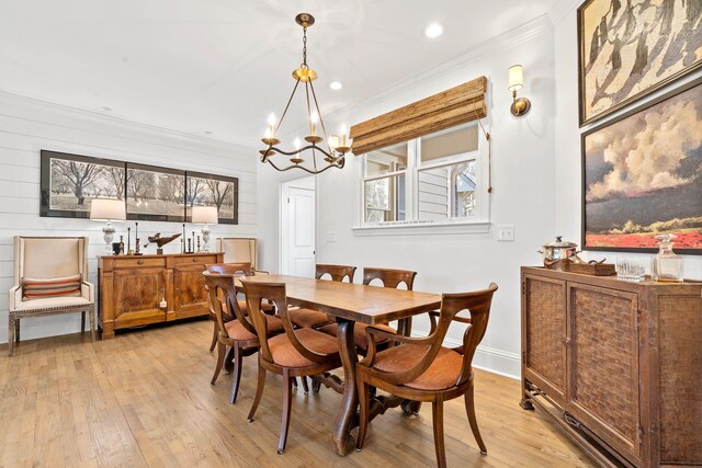 dining area with ornamental molding, light hardwood / wood-style floors, and a notable chandelier