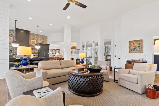 living room featuring crown molding, ceiling fan, light hardwood / wood-style floors, and ornate columns