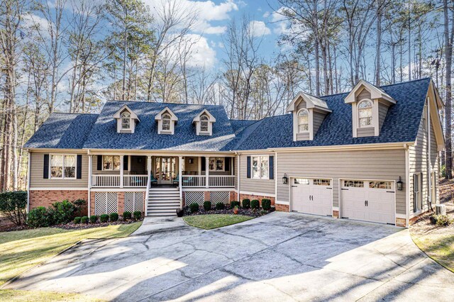 cape cod home featuring a garage, a front yard, and covered porch