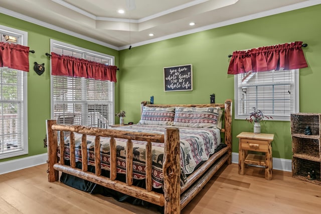 bedroom featuring crown molding, wood-type flooring, and a raised ceiling