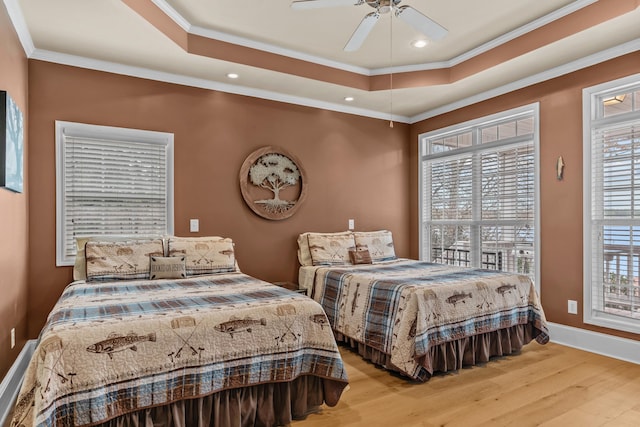 bedroom with a raised ceiling, crown molding, and light hardwood / wood-style floors