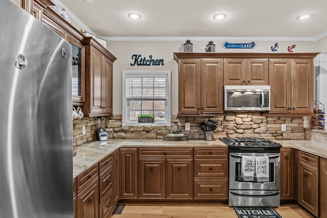 kitchen featuring light stone counters, ornamental molding, and appliances with stainless steel finishes