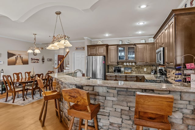 163 Knight Dr, Milledgeville, GA 31061 - kitchen with stainless steel appliances, light stone counters, a breakfast bar area, tasteful backsplash, and ornamental molding